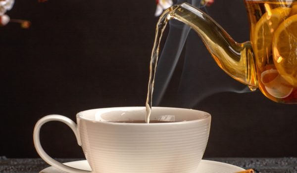 front-view-cup-tea-with-lemon-cinnamon-kettle-grey-desk front-view-cup-tea-with-lemon-cinnamon-kettle-grey-desk